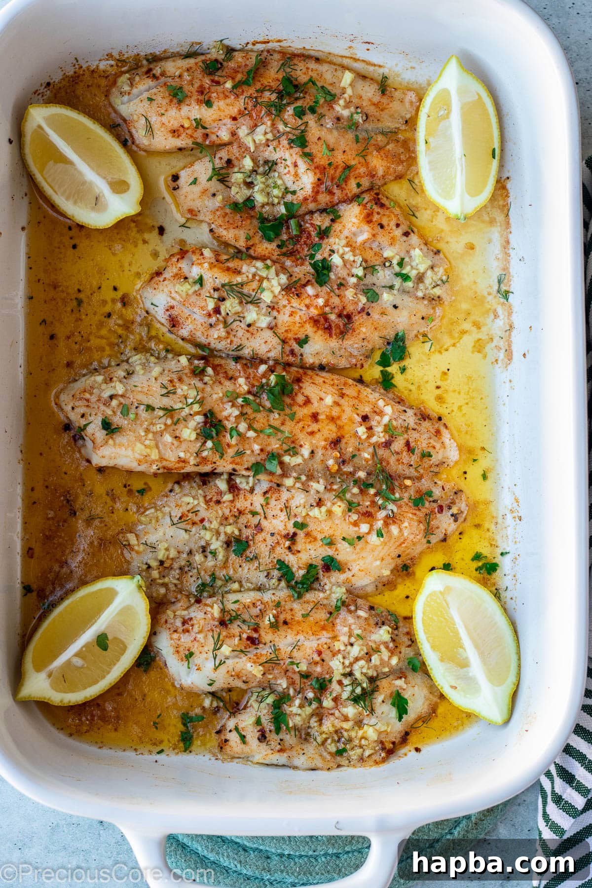 Freshly baked tilapia fillets arranged neatly in a baking dish, perfectly golden.