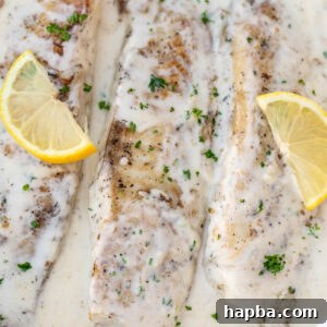 Fish in white sauce with lemon slices, a perfectly presented dish.