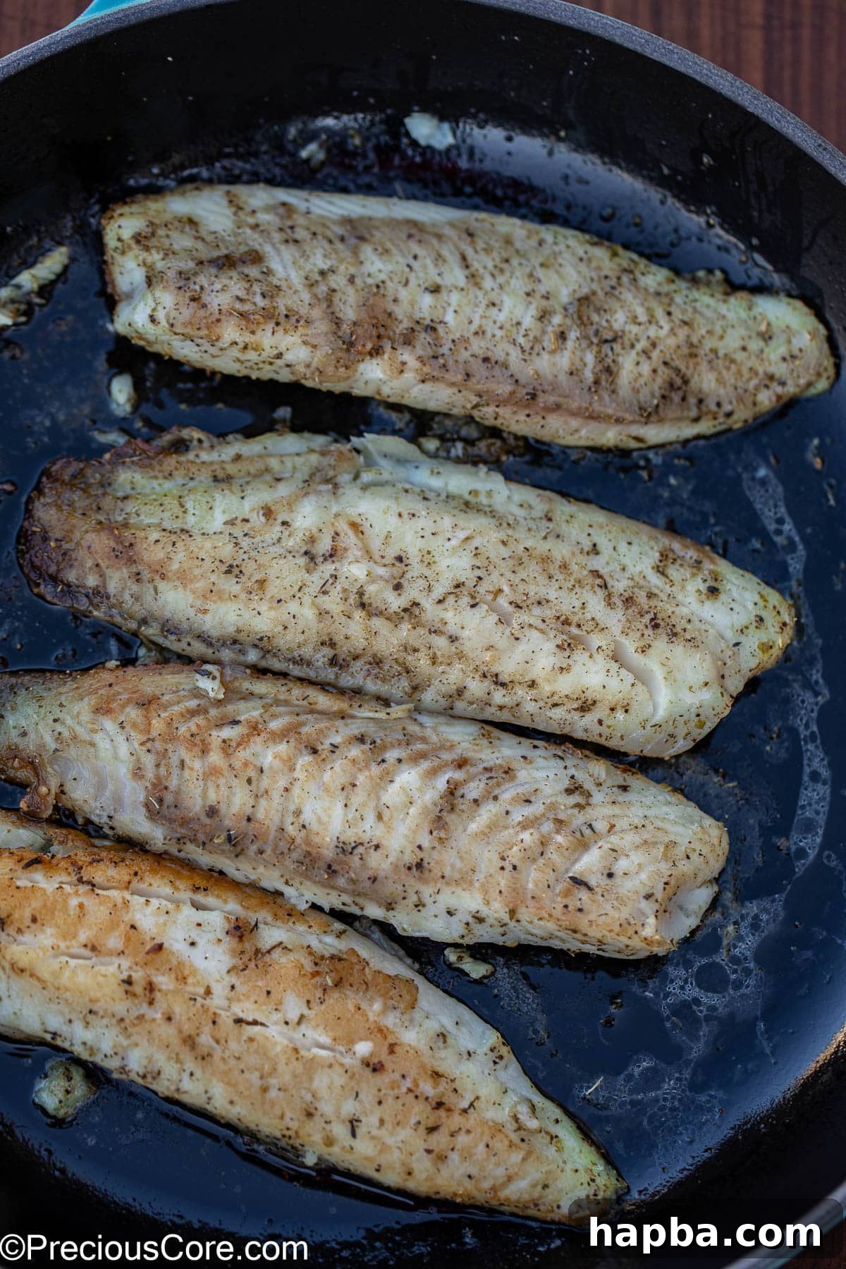 Creamy White Sauce Fish 6 Seasoned and perfectly seared fish fillets resting in a hot pan.