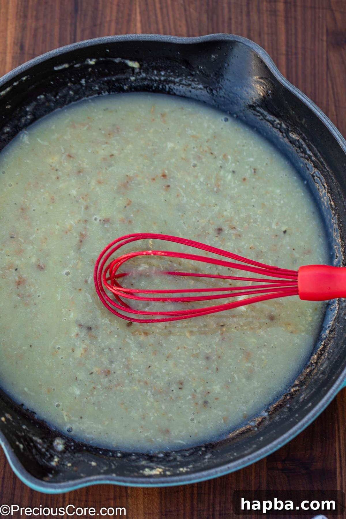 Creamy White Sauce Fish 8 A whisk smoothly blending the white sauce ingredients in a pan, creating a creamy texture.