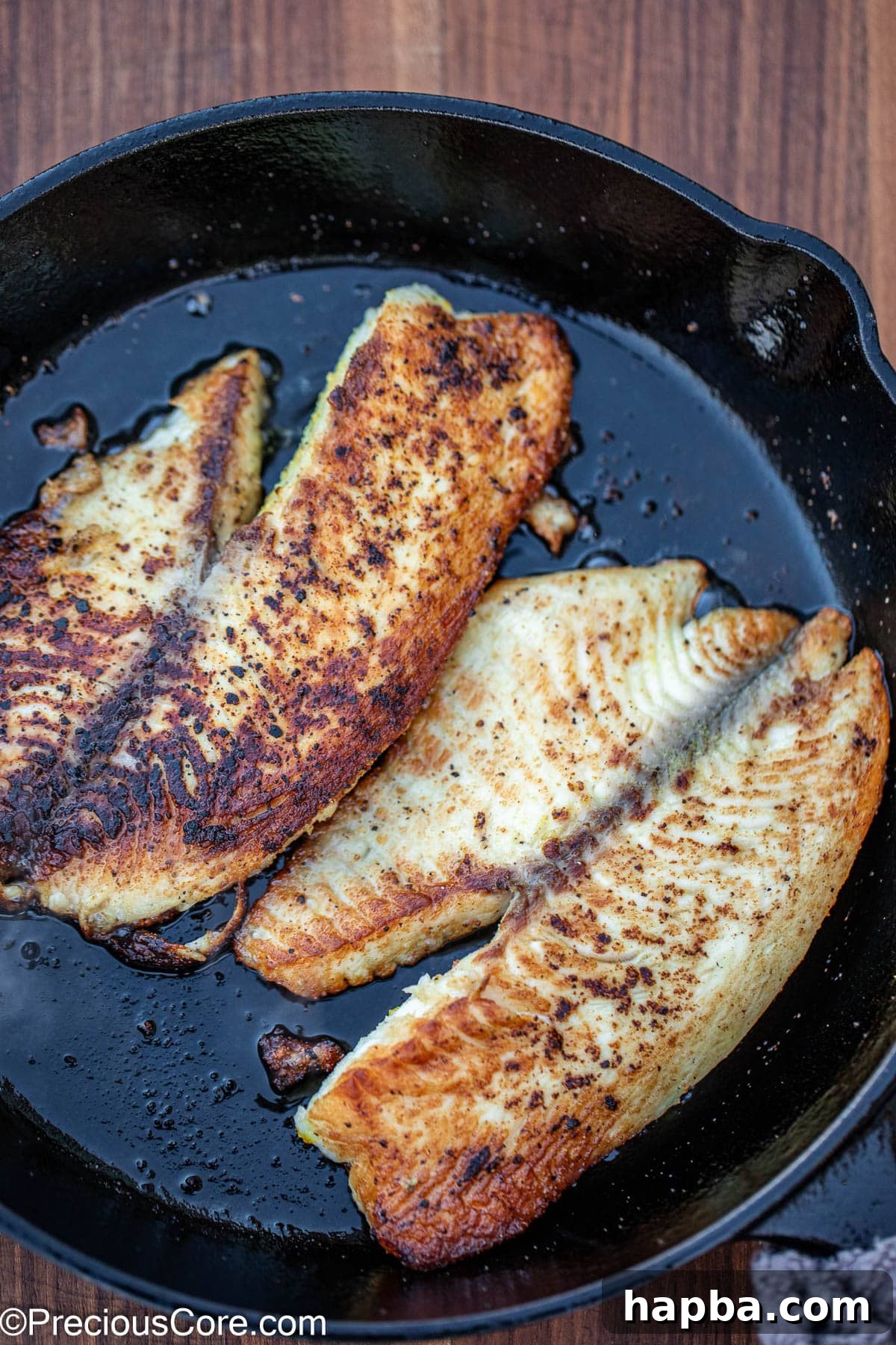 Zesty Lemon Pepper Tilapia 6 2 cooked fish fillets in a cast iron skillet.