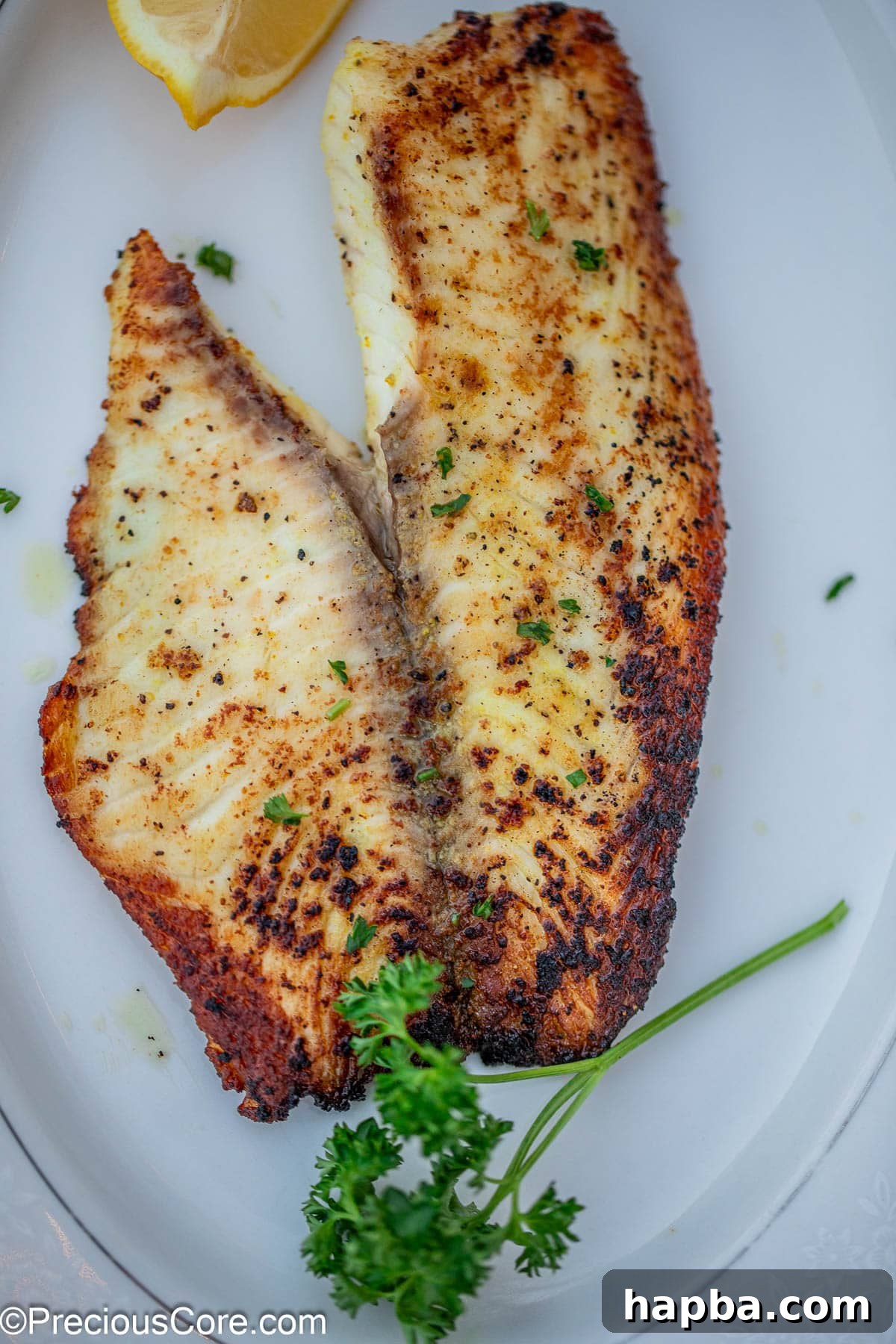 Zesty Lemon Pepper Tilapia 8 A cooked fish fillet garnished with minced parsley.