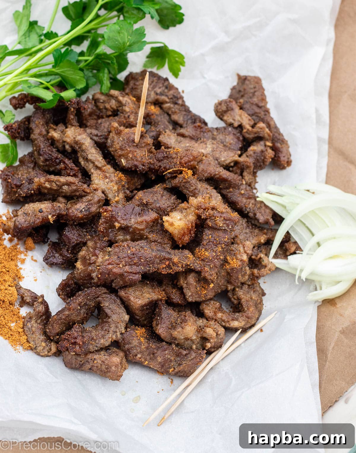 Cameroonian Soya Morsels 2 Cameroonian grilled meat on parchment paper, served with onions and soya pepper, showcasing a vibrant and delicious dish.