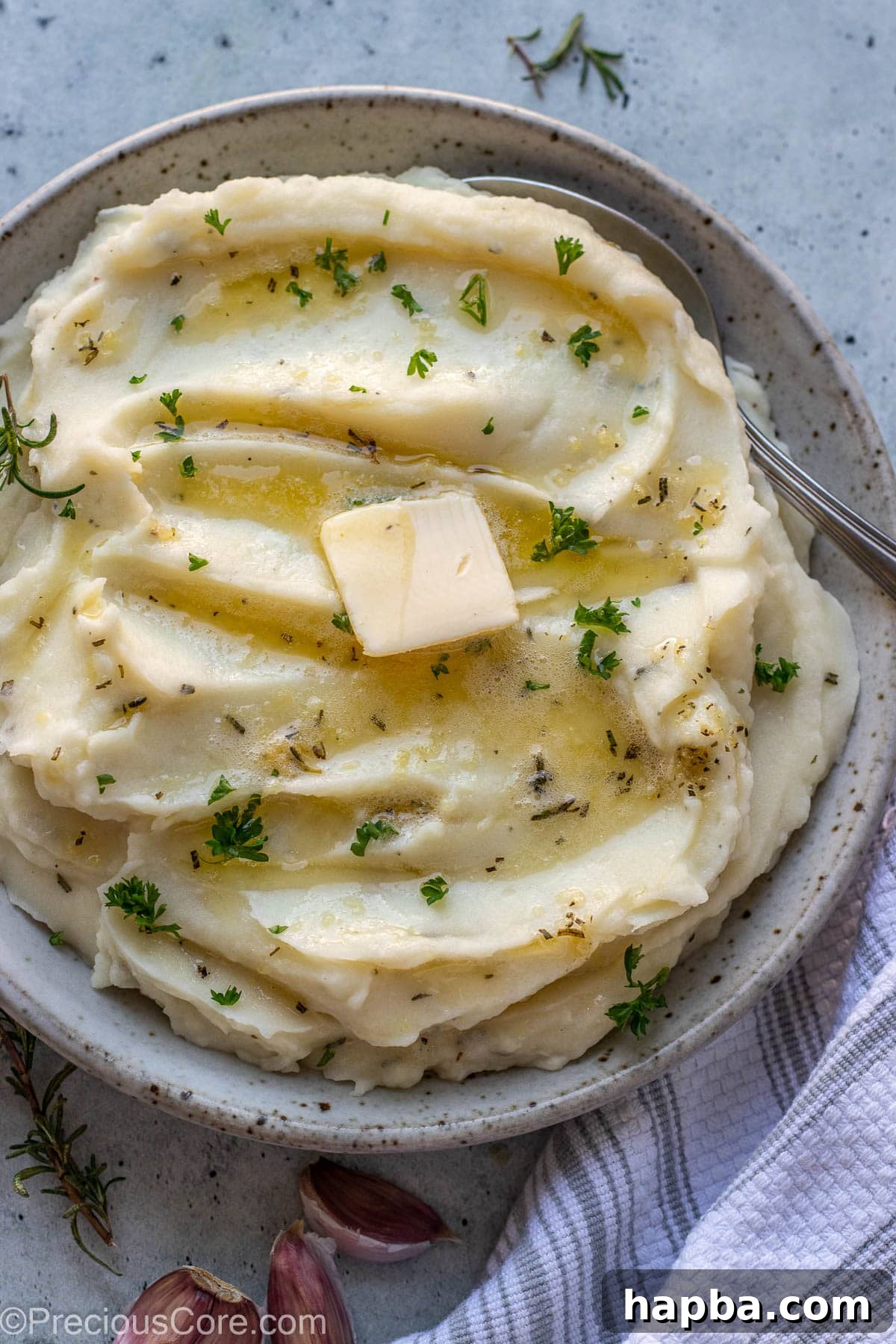 Rosemary Garlic Mashed Potatoes in a bowl topped with melted butter and parsley.