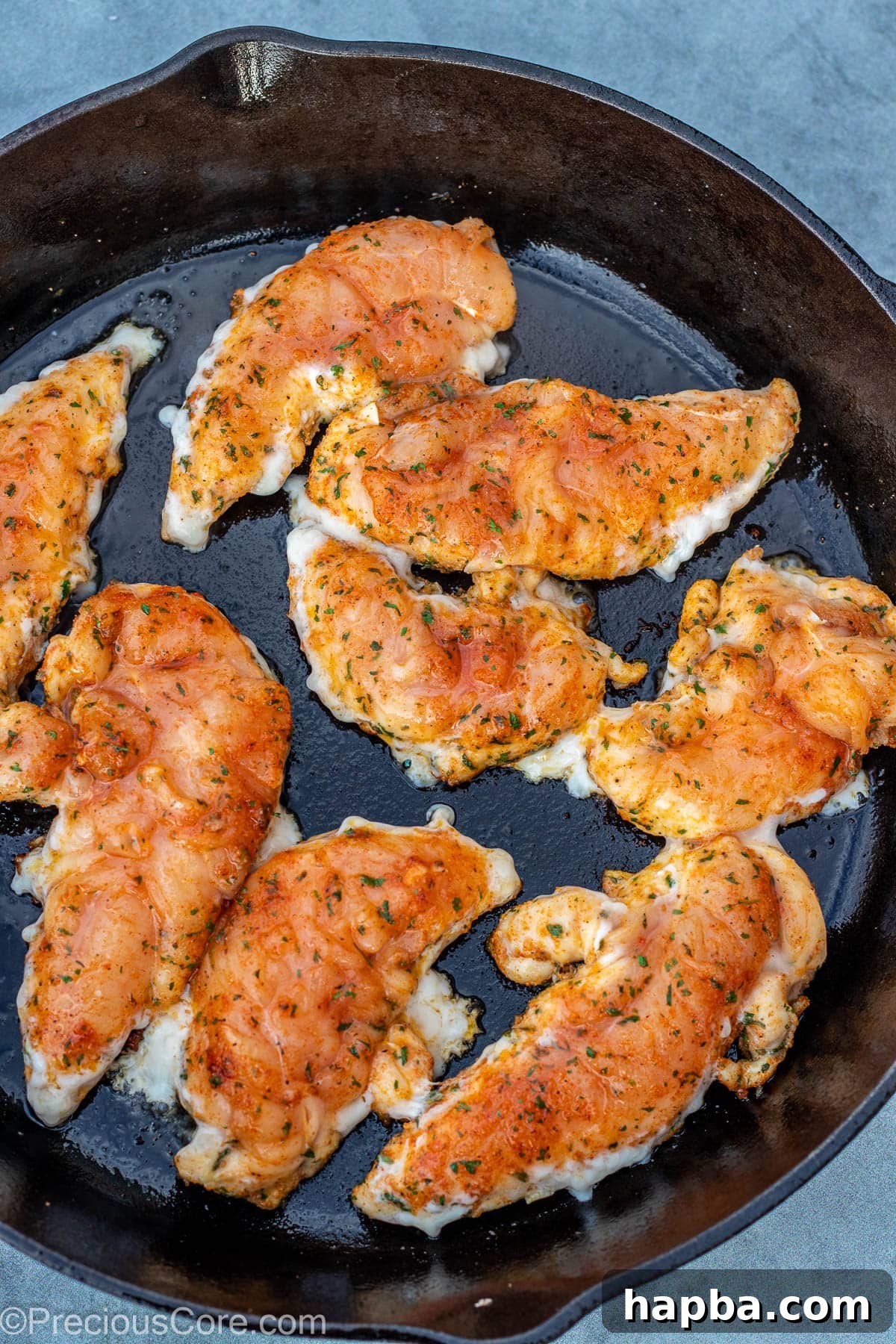 Crispy Pan-Seared Chicken Tenders 6 Raw seasoned chicken tenders being carefully placed into a hot skillet with oil.