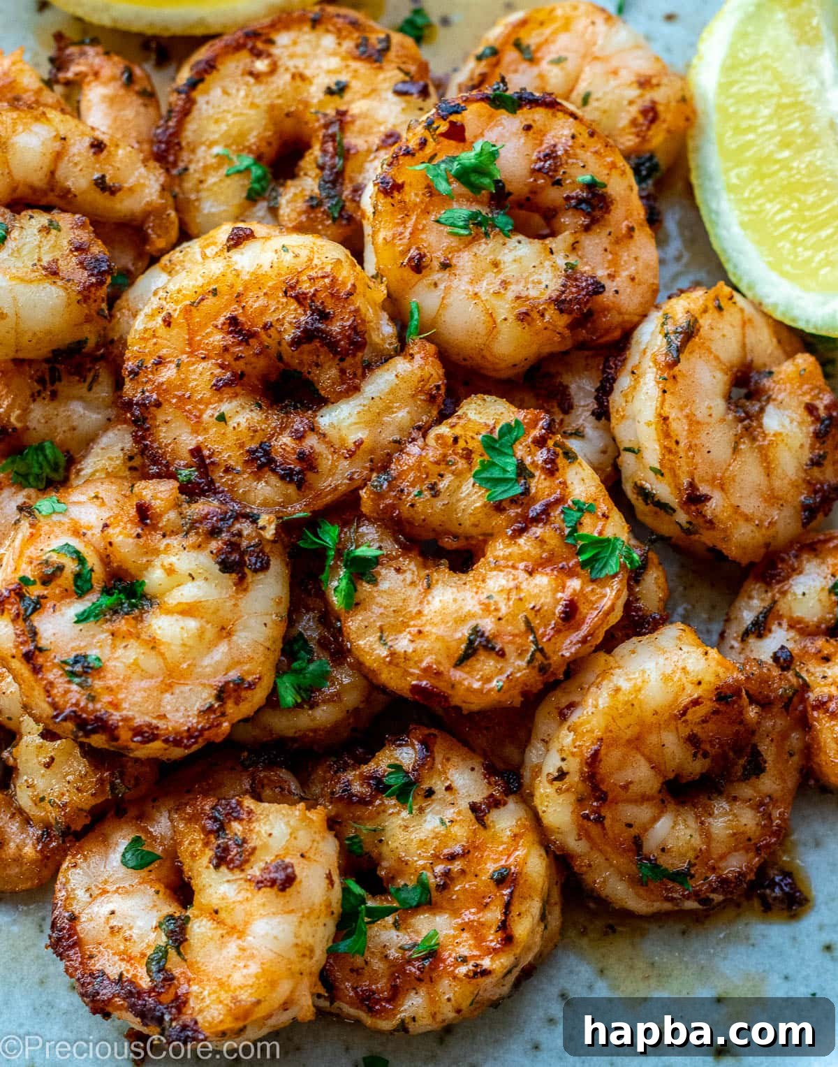 Pan Seared Shrimp on a plate, garnished with fresh herbs and lemon wedges.