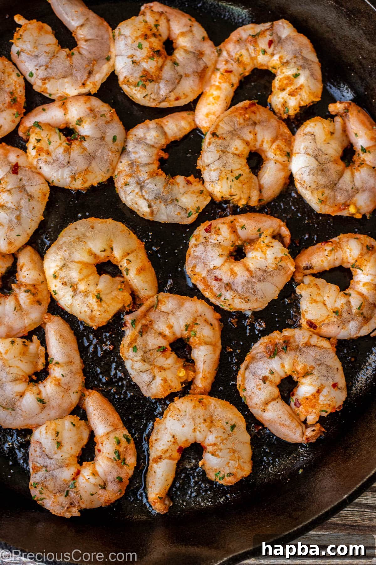 Seasoned shrimp being pan-seared in a 12-inch cast iron skillet.