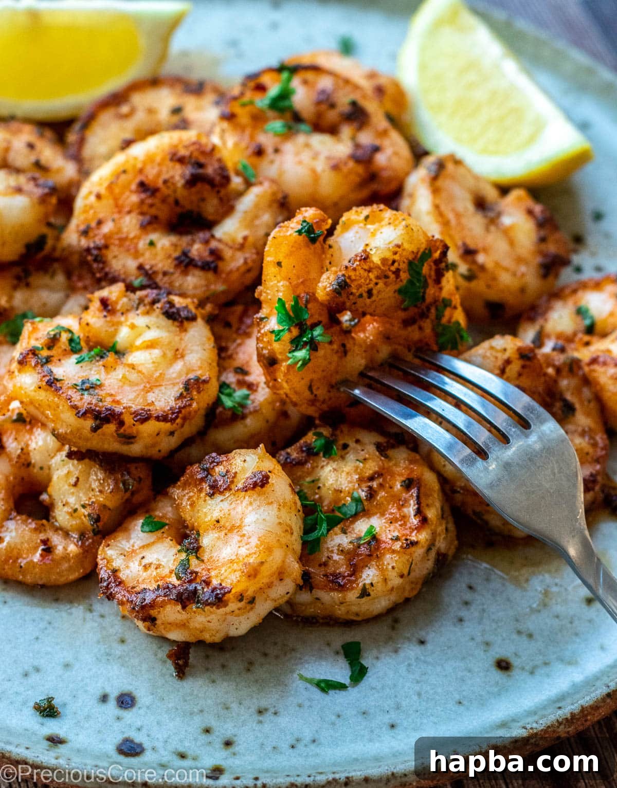 Cooked shrimp on a plate with lemon wedges, ready to serve.