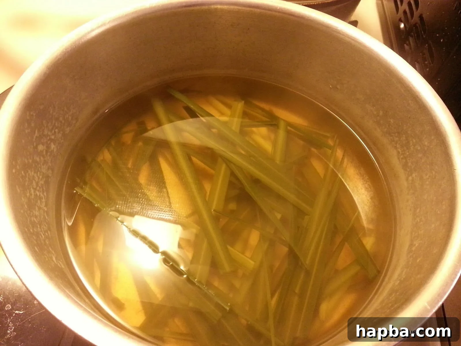 A steaming, clear glass cup of freshly brewed lemongrass tea, garnished with fresh lemongrass stalks and a slice of lemon on the side, inviting a sense of calm.