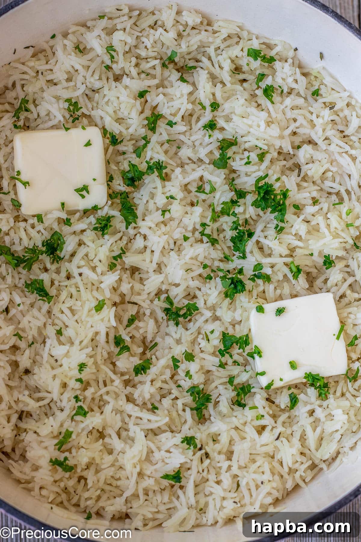 Perfectly cooked garlic herb rice garnished with melting butter and freshly minced parsley, enhancing its aroma and presentation.