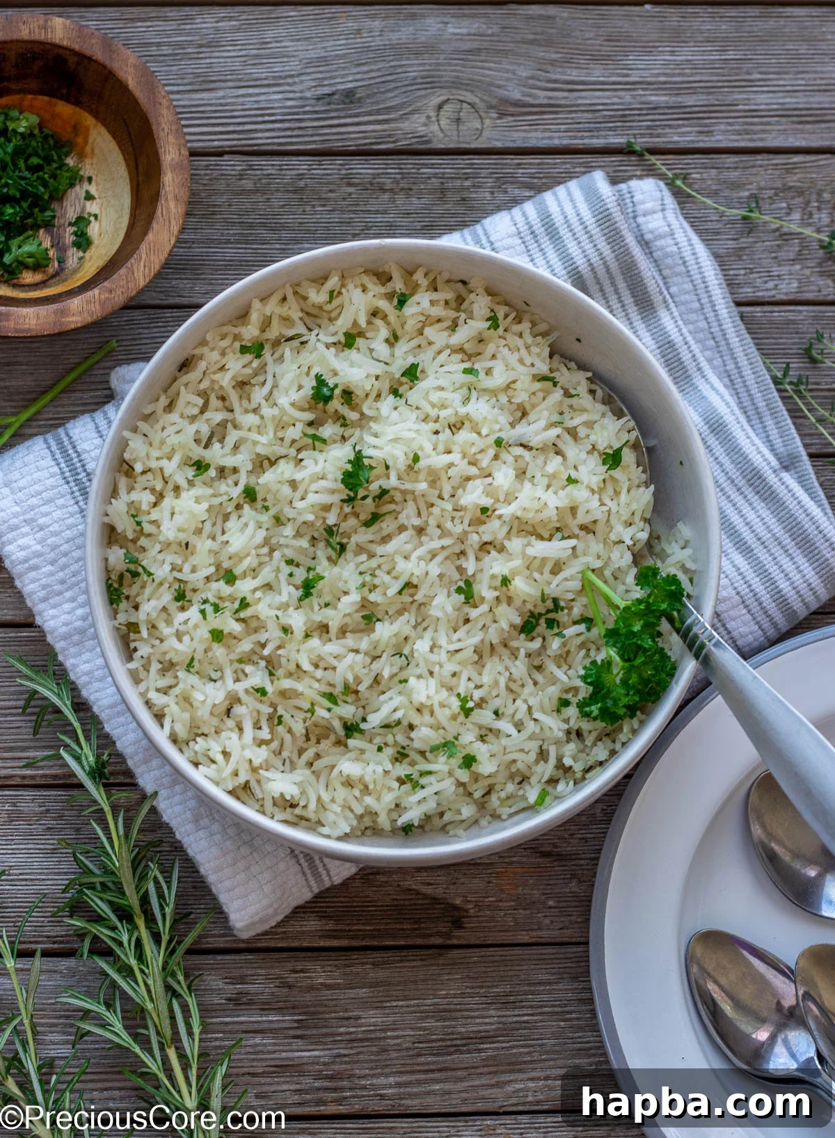 A stylish shot of a bowl of seasoned garlic herb rice with neatly stacked plates on the side, ready for a meal.