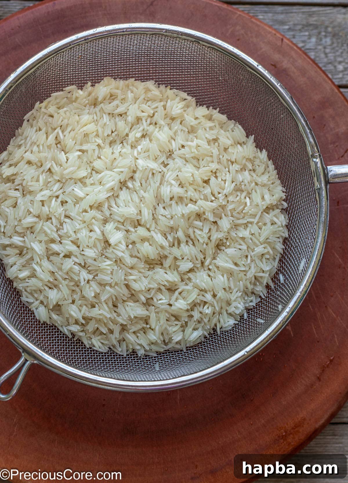 Clean, rinsed Basmati rice draining in a fine mesh strainer, preparing for the cooking process.