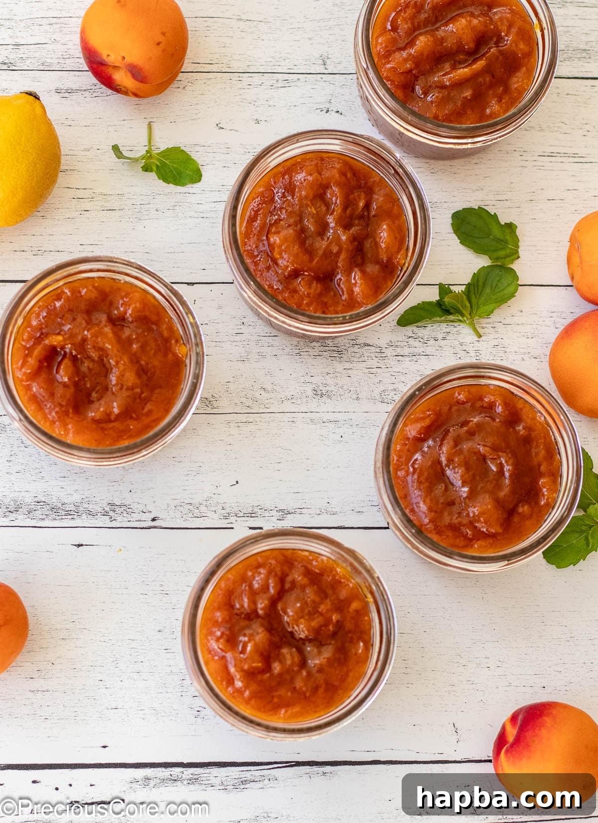Sunshine Apricot Spread 11 Five open mason jars, freshly filled with golden apricot preserves, lined up on a surface.