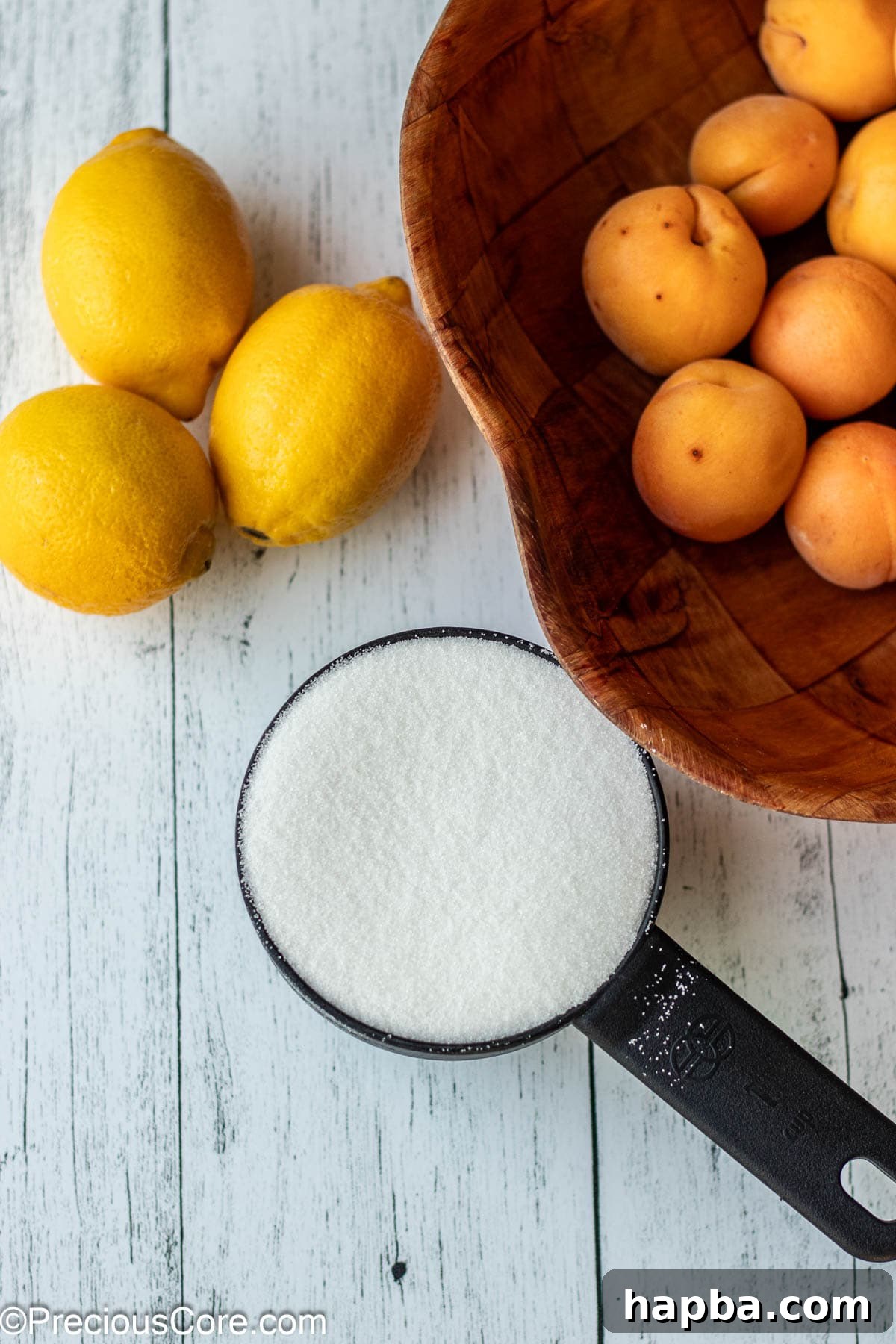 Sunshine Apricot Spread 4 Fresh apricots, bright yellow lemons, and granulated sugar laid out on a wooden board, ready for preserve making.