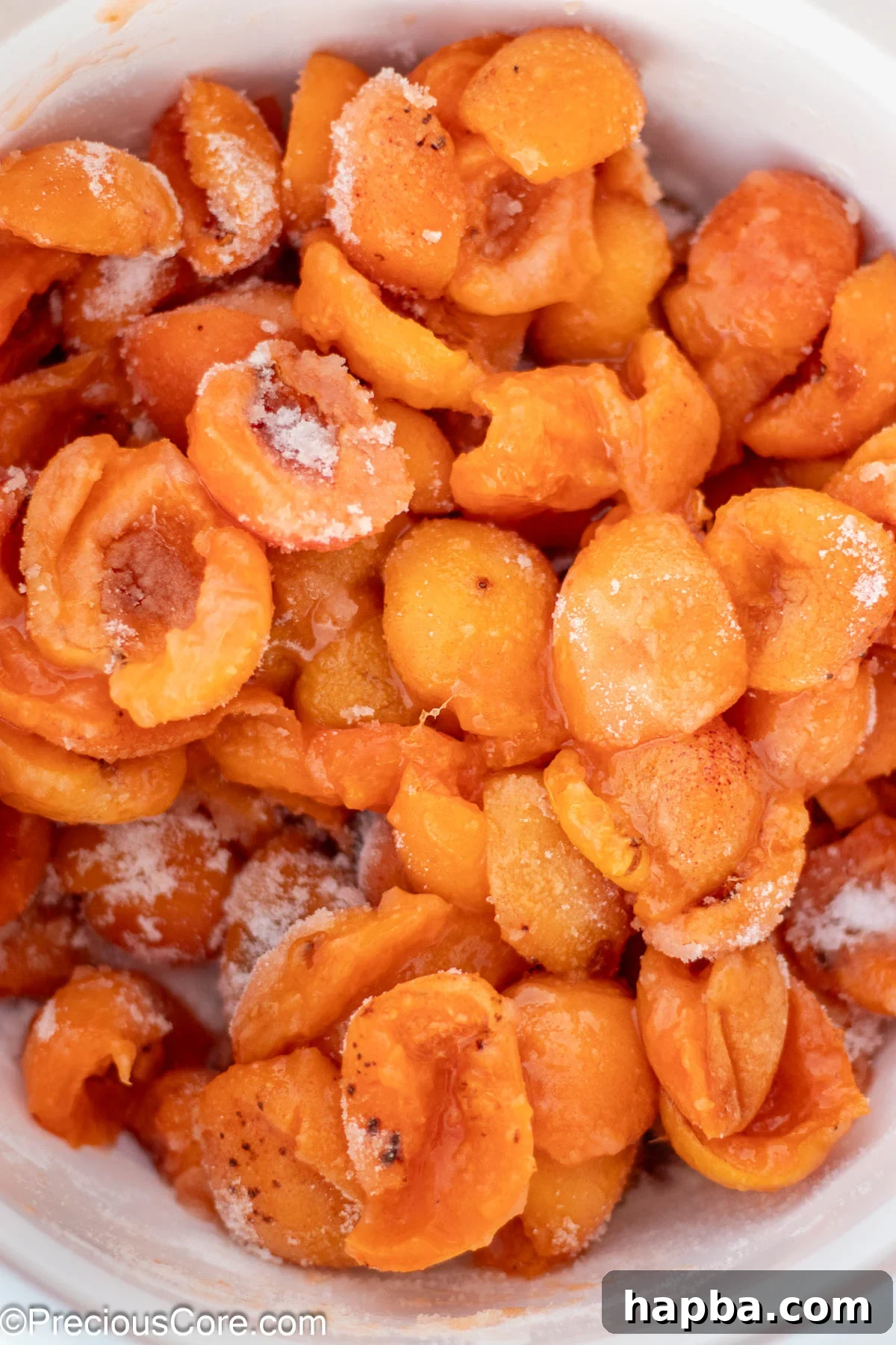 Sunshine Apricot Spread 6 Halved apricots glistening, mixed with granulated sugar and lemon juice in a white ceramic bowl.