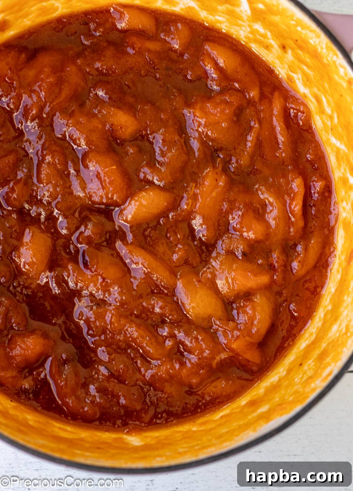 Sunshine Apricot Spread 8 Apricot preserves simmering in an enameled cast iron pot on a stovetop.