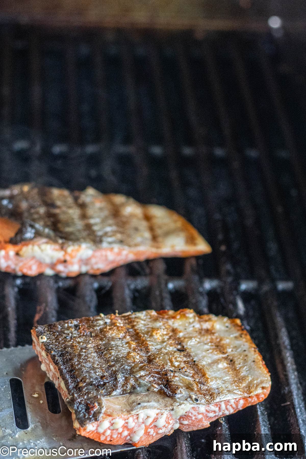 Skin-on sockeye salmon cooking on a hot grill, showing distinct grill marks.