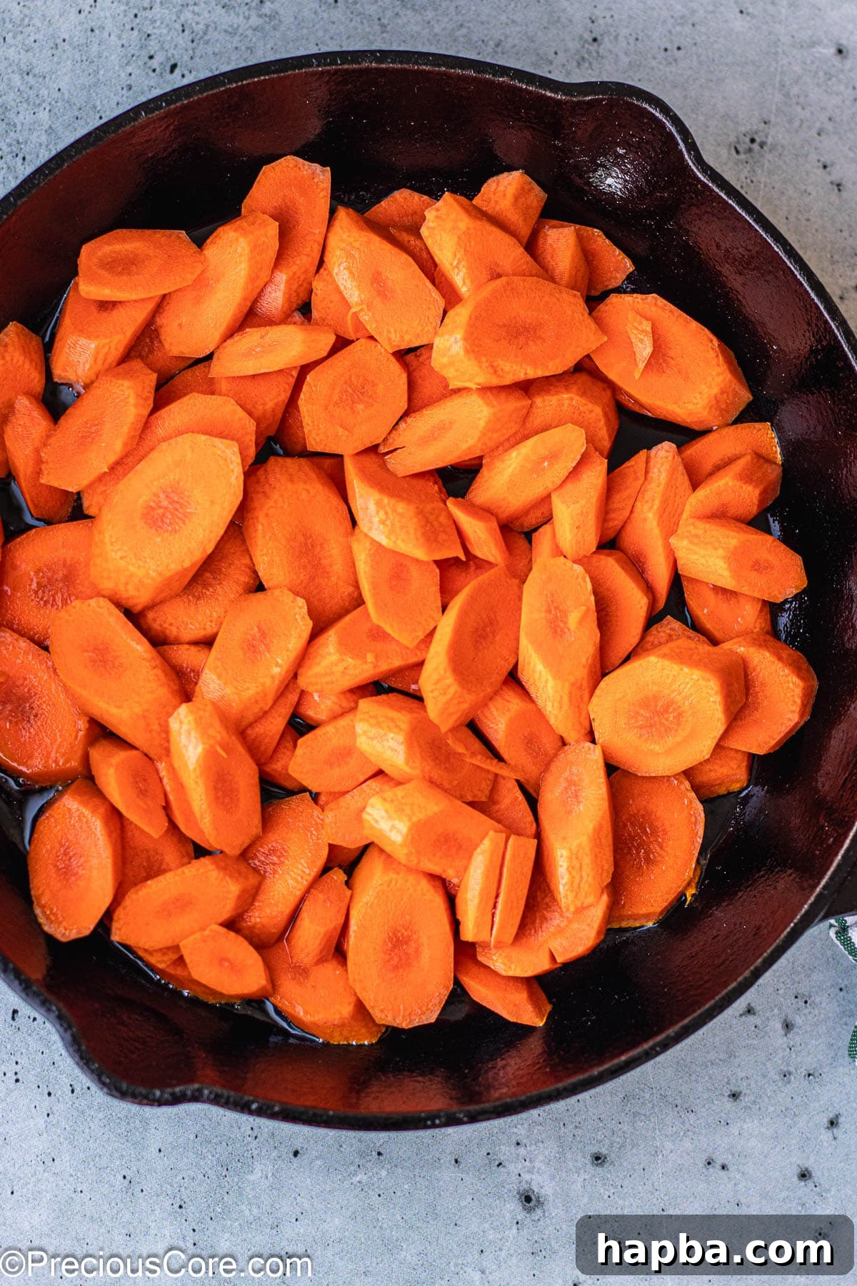 Caramelized Carrots 5 Sliced carrots sizzling in olive oil within a hot cast iron skillet, mid-frying process.