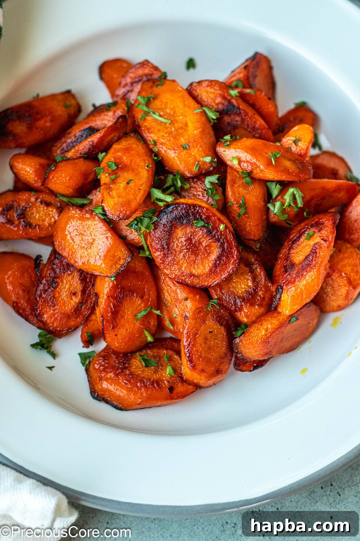 Caramelized Carrots 7 A serving of golden-brown fried carrots, garnished with fresh parsley, on a pristine white plate.