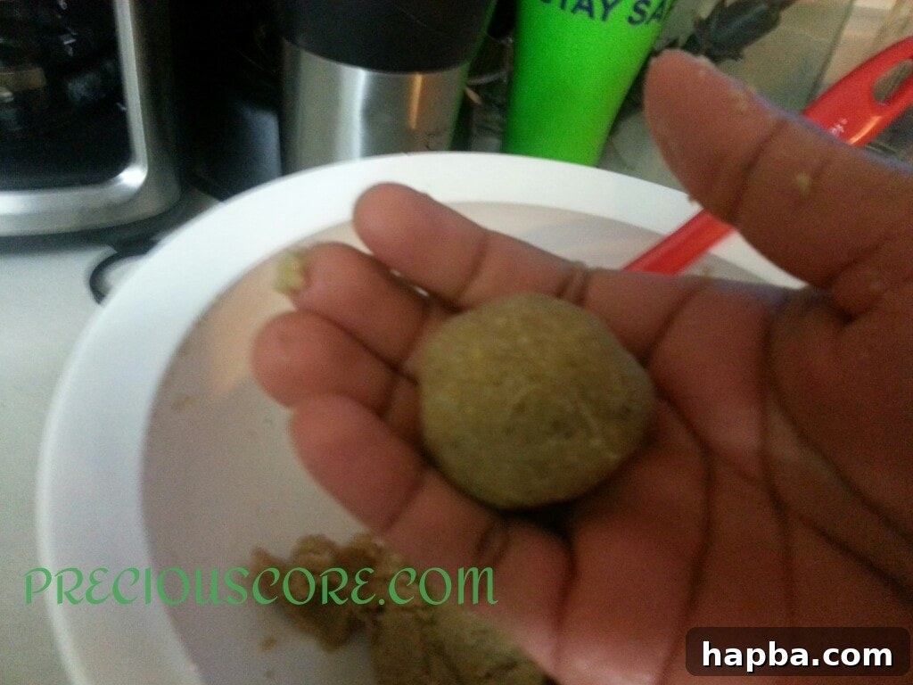 Accra Banana batter being carefully dropped into hot oil for frying.
