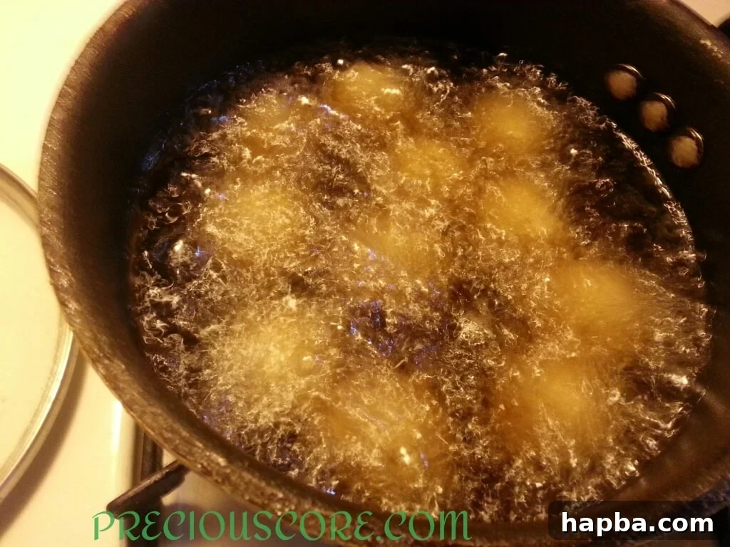 Accra Banana fritters frying in hot oil, turning golden brown.