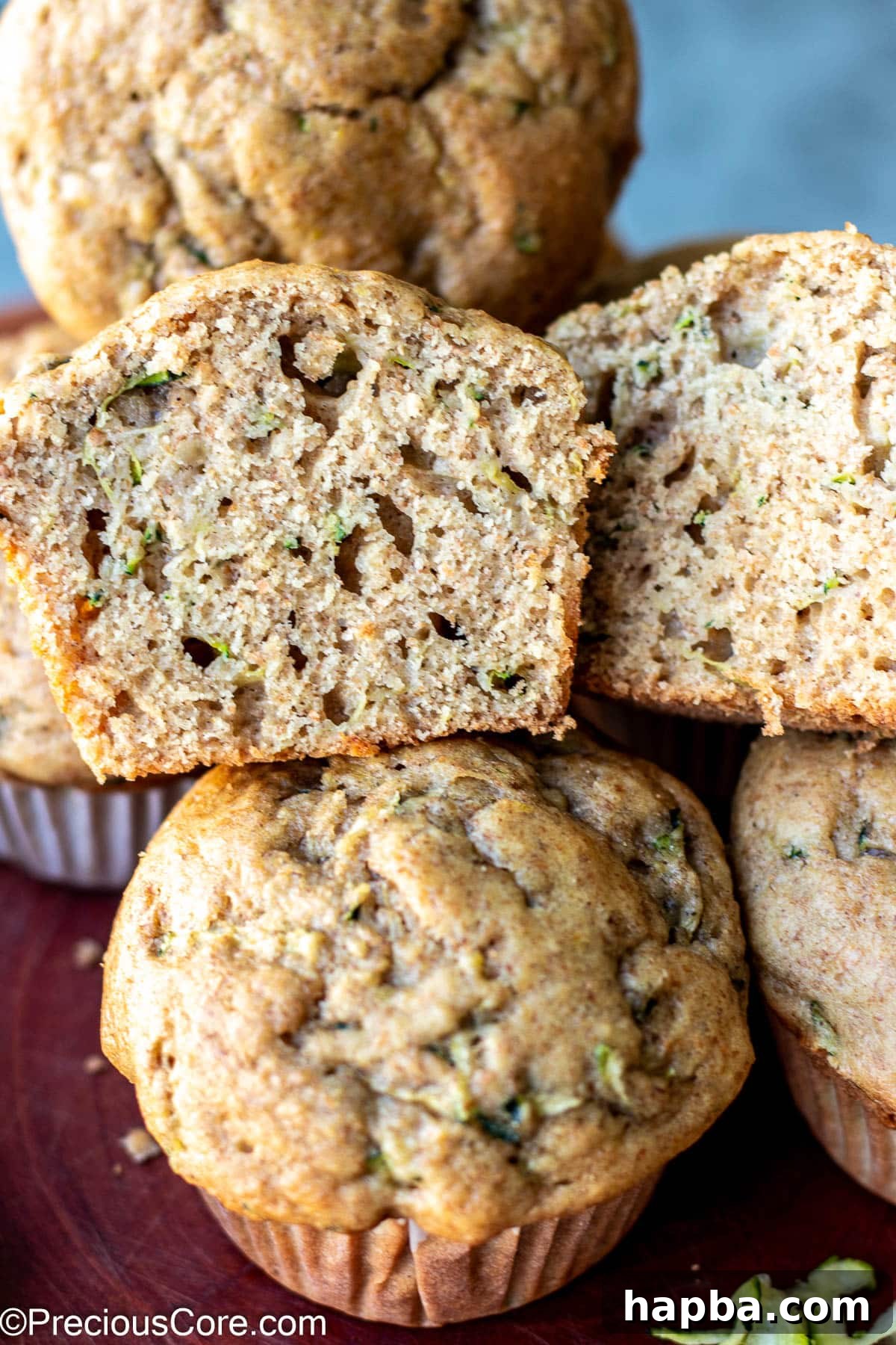 Wholesome Zucchini Applesauce Muffins 2 Zucchini muffin cut in half to show its soft, moist texture, revealing flecks of green zucchini.