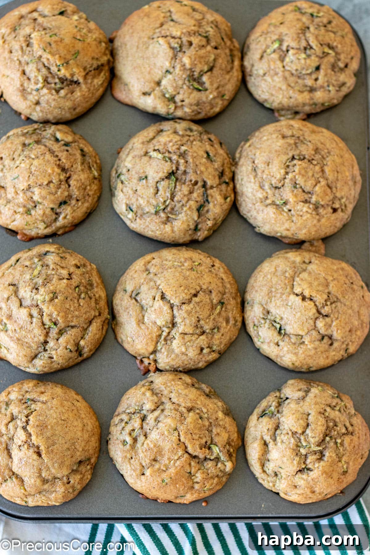 Wholesome Zucchini Applesauce Muffins 12 Freshly baked zucchini muffins, golden brown and puffed, cooling in their muffin tin after being removed from the oven.