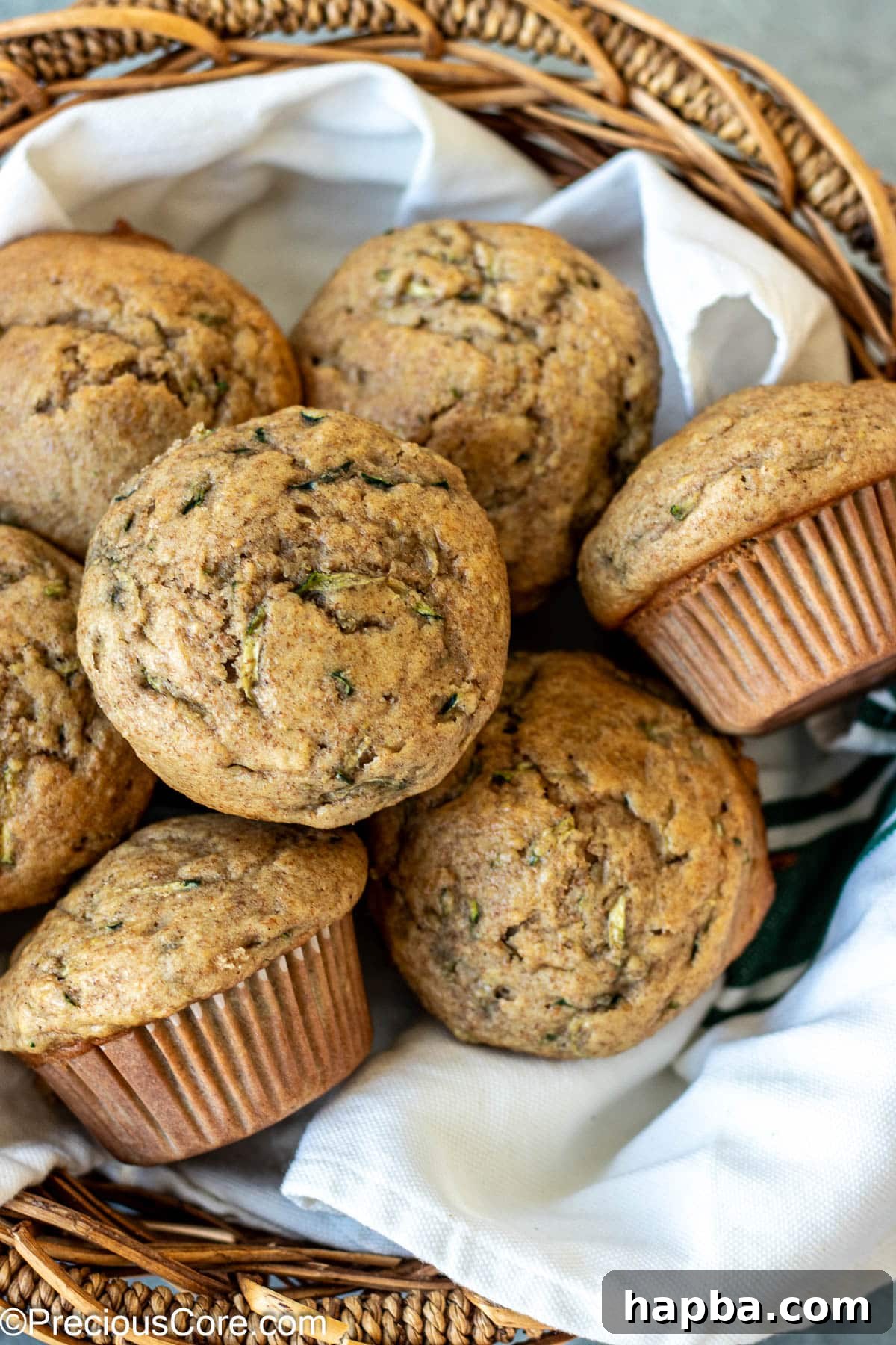 Wholesome Zucchini Applesauce Muffins 3 Freshly baked zucchini applesauce muffins nestled in a charming basket lined with a clean kitchen cloth, ready for serving.