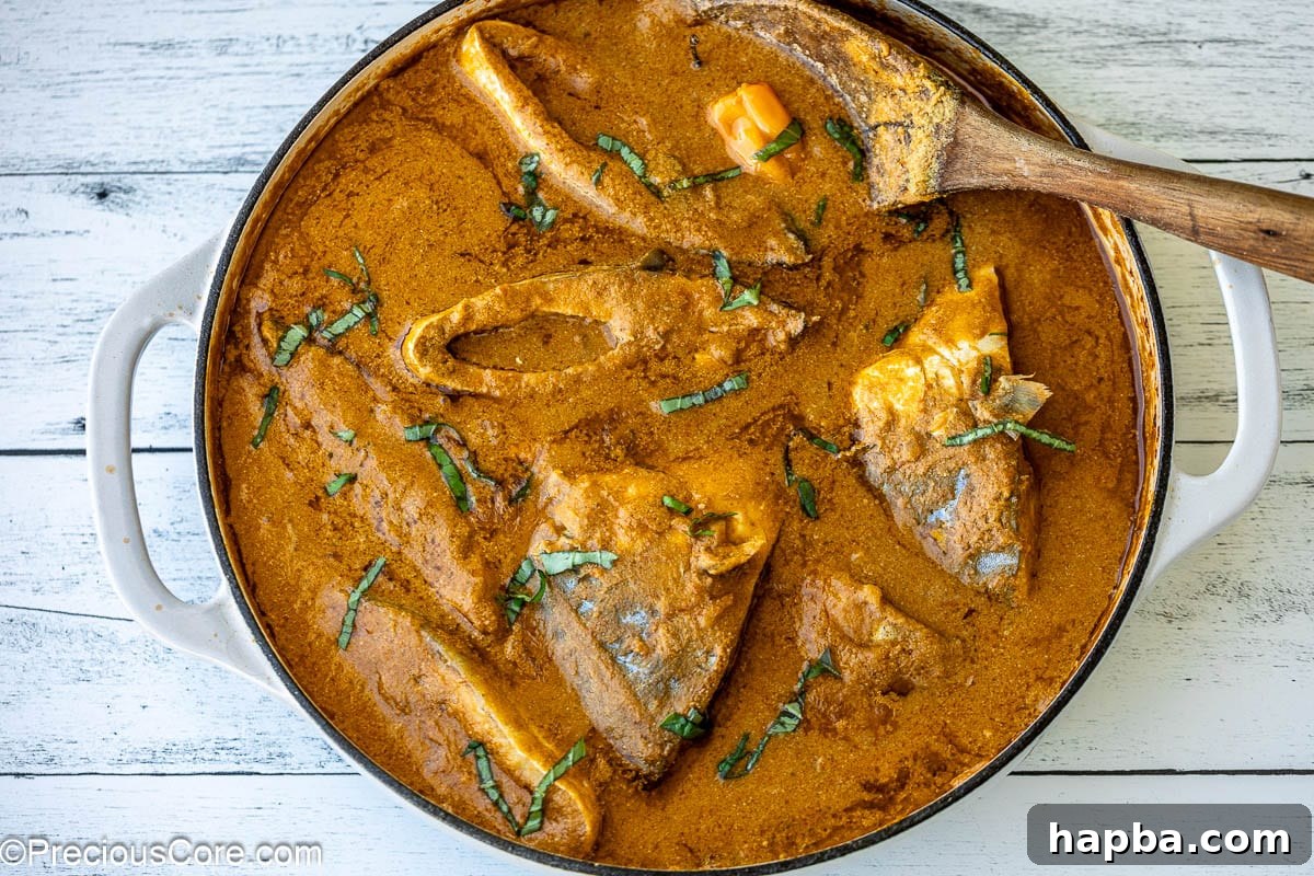 A white pot brimming with rich, reddish-brown stew and succulent fish steaks, ready to be served.