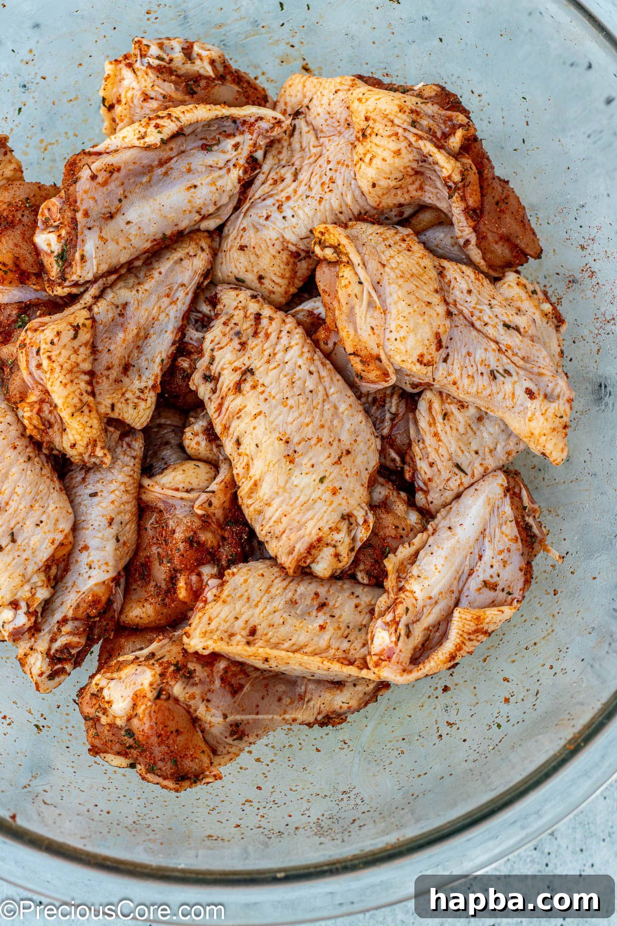 Crispy Baked Dry Rub Wings 5 Chicken wings coated evenly with a homemade dry rub seasoning in a mixing bowl.