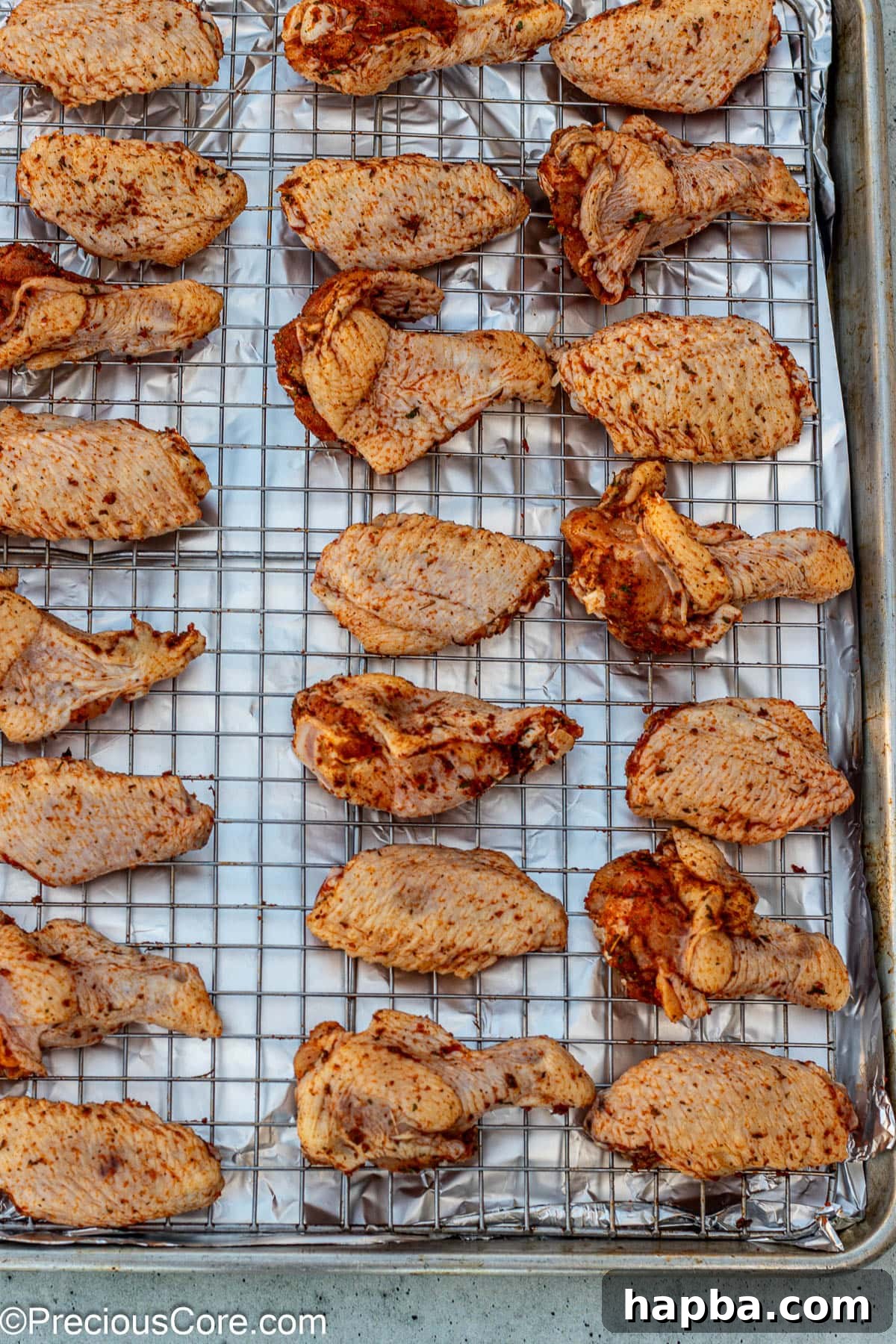 Crispy Baked Dry Rub Wings 6 Dry rub seasoned chicken wings arranged in a single layer on an oven-safe wire rack over a baking sheet.