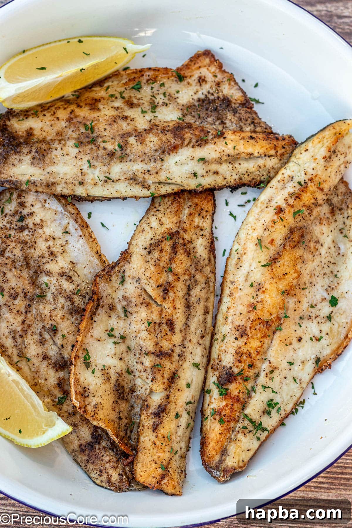 Crispy-Skinned Sea Bass 2 Crispy Pan Seared Sea Bass fillets garnished with fresh herbs on a white plate, ready to serve.