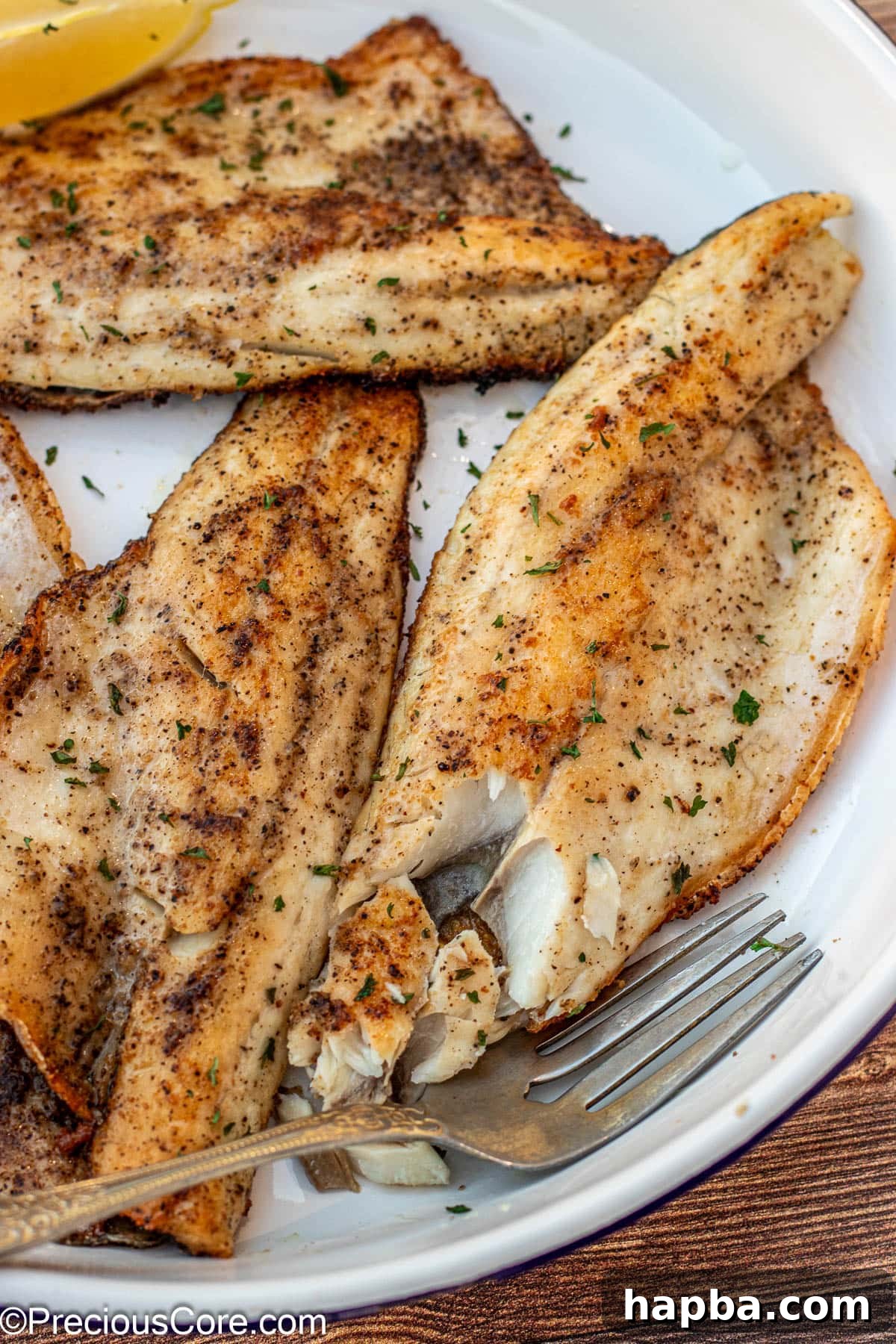 Crispy-Skinned Sea Bass 3 A fork flaking a piece of cooked sea bass to demonstrate its tender, flaky texture and perfect doneness.