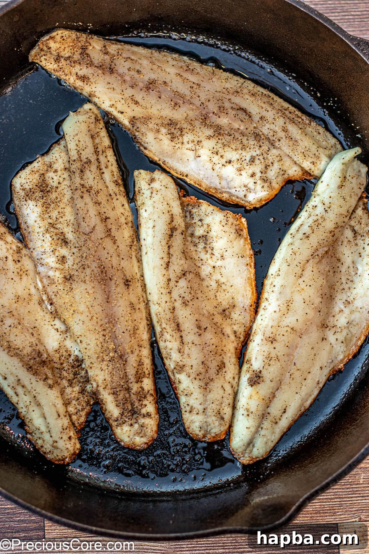 Crispy-Skinned Sea Bass 6 Multiple sea bass fillets cooking skin-side down in a hot 12-inch cast iron skillet with shimmering olive oil.