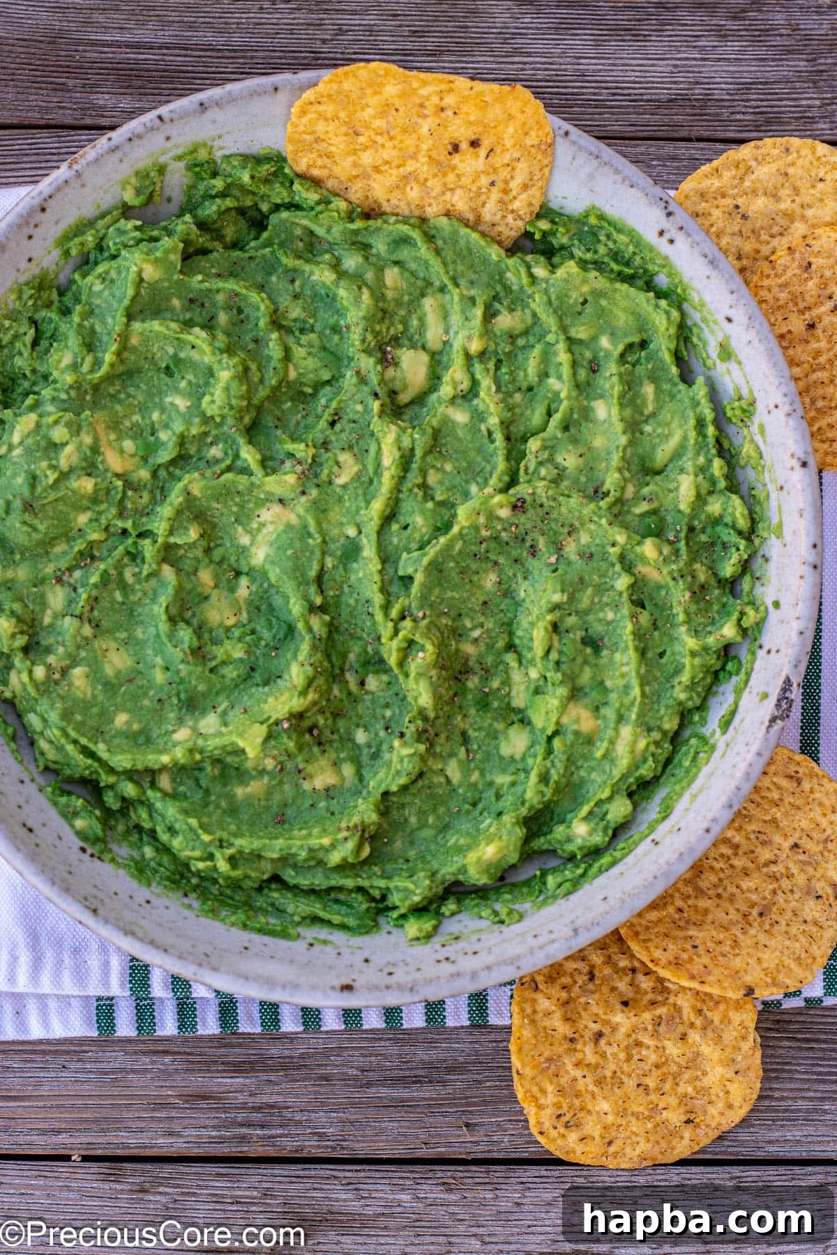 Effortless 4 Ingredient Guacamole 2 Creamy 4-ingredient guacamole in a bowl with a tortilla chip stuck in, ready for serving.