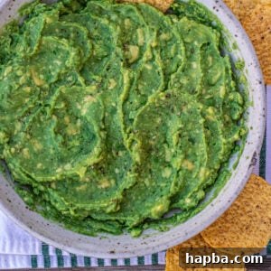 Creamy 4-ingredient guacamole in a bowl with a tortilla chip stuck in, ready for serving.