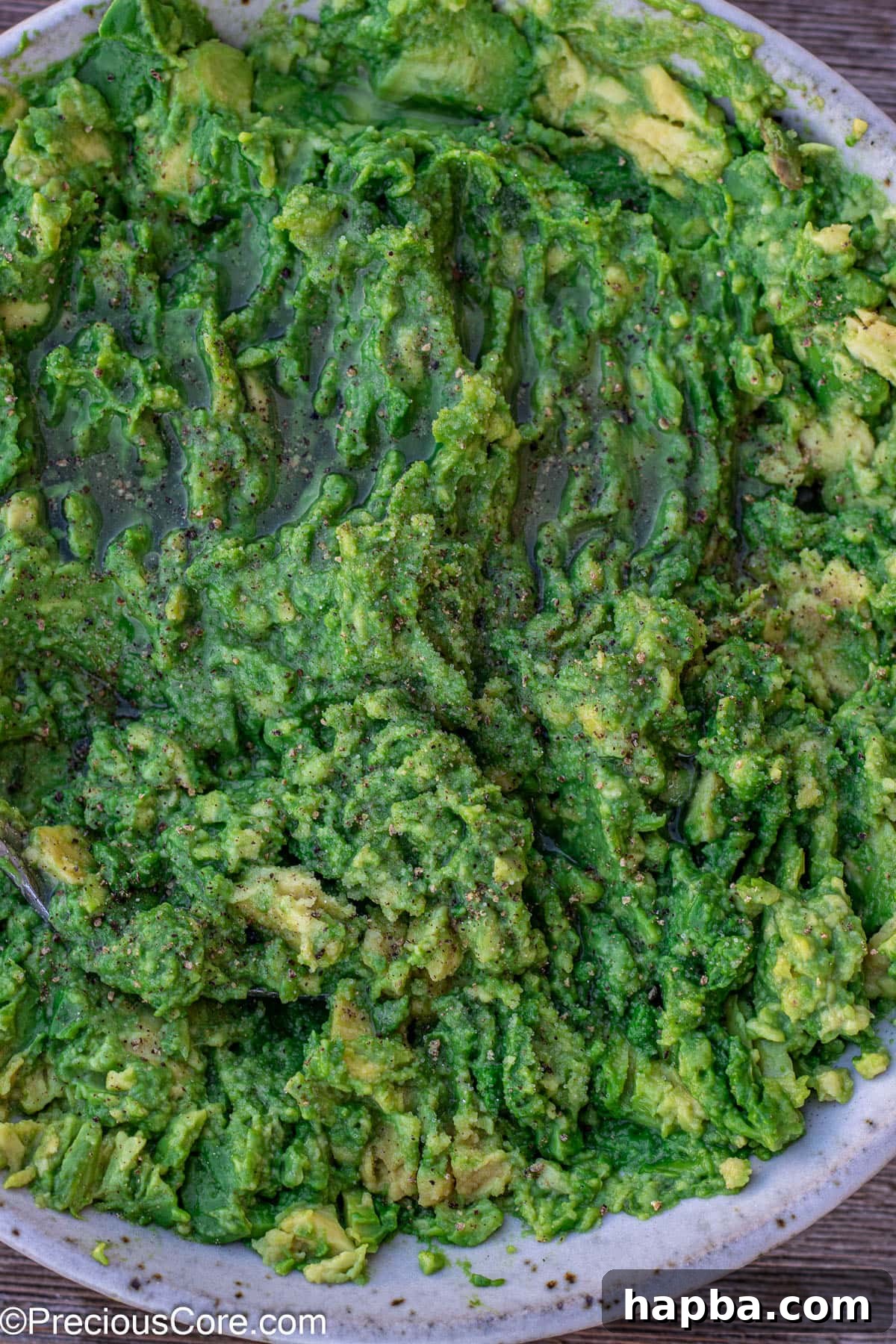 Effortless 4 Ingredient Guacamole 10 Salt, pepper, and lime juice drizzled over mashed avocados, ready to be mixed.