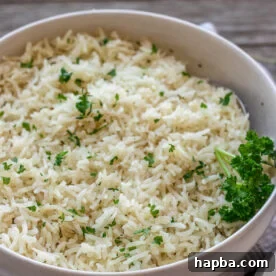 A bowl of flavorful garlic herb rice topped with minced fresh parsley.