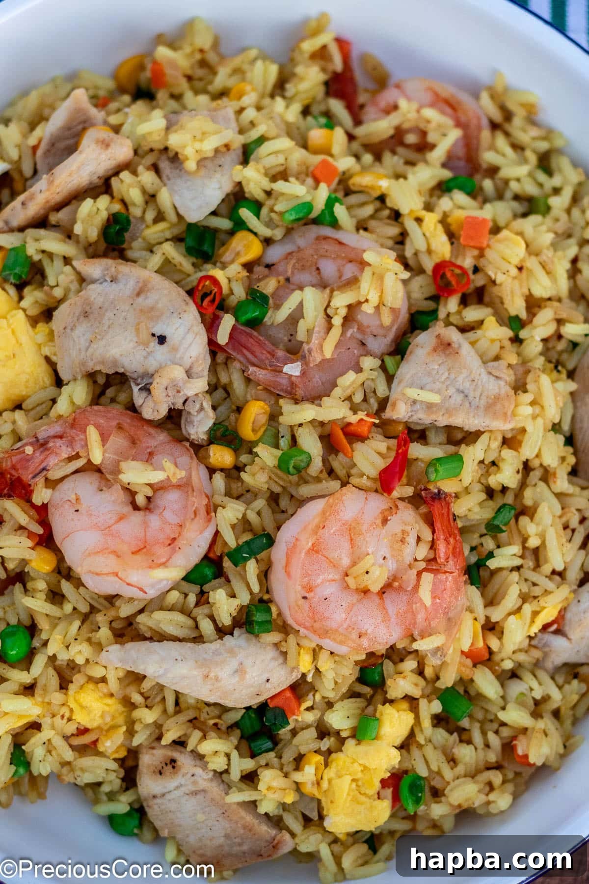 A vibrant dish of homemade shrimp and chicken fried rice, loaded with juicy chunks of chicken and shrimp, presented in a pristine white serving dish.