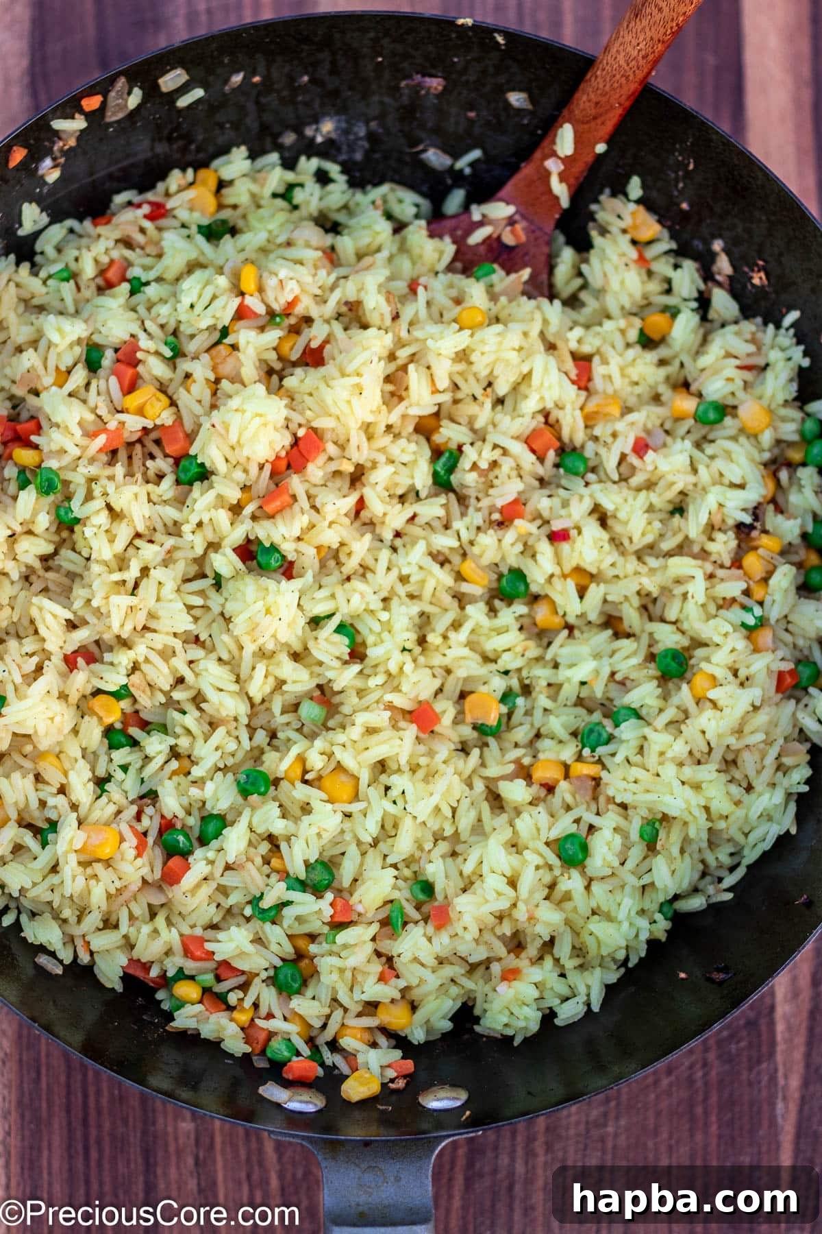 Fluffy rice being stir-fried with the aromatic vegetables in a wok, absorbing the delicious flavors.
