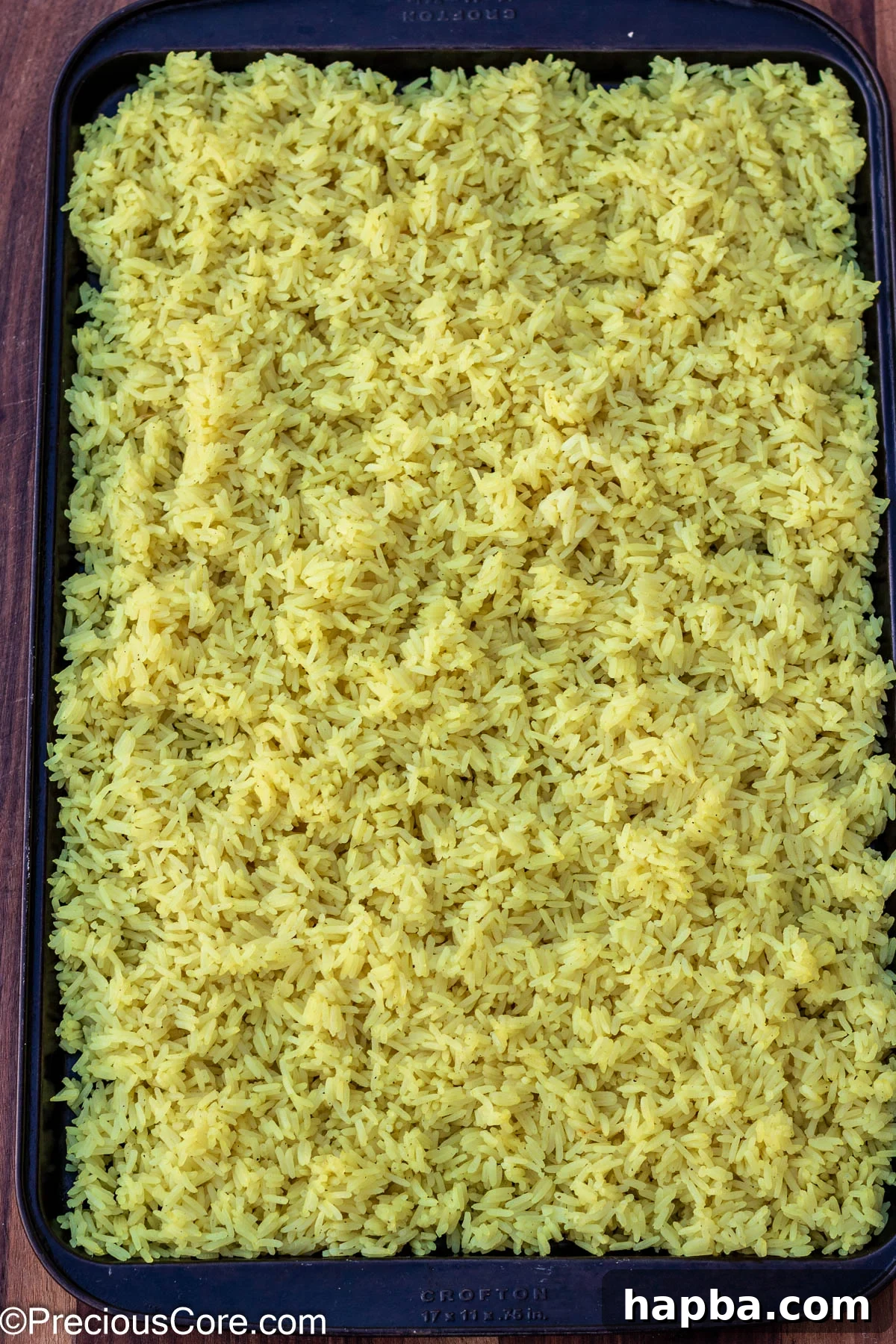 Cooked jasmine rice spread thinly on a baking tray, cooling and drying out for optimal fried rice texture.