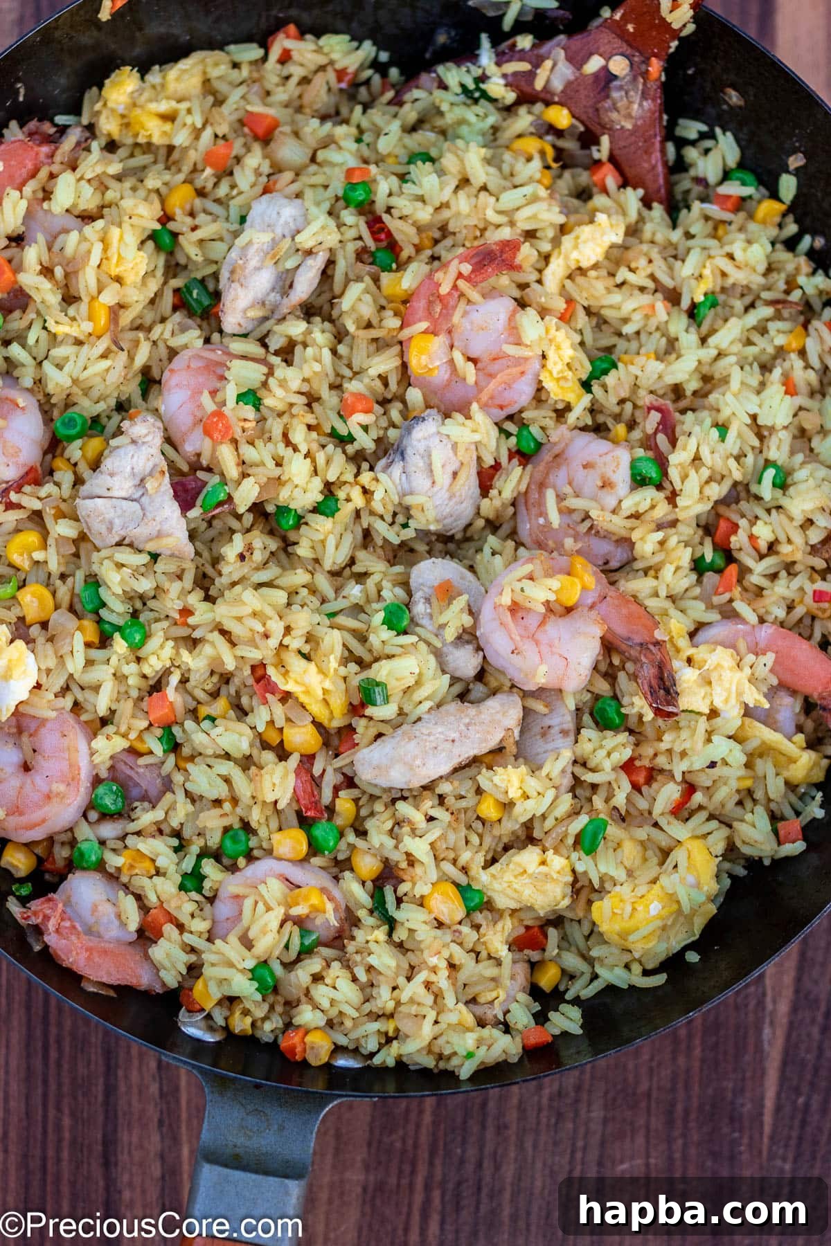 The delicious shrimp and chicken fried rice being expertly stir-fried in a hot wok, showcasing the vibrant colors and textures.