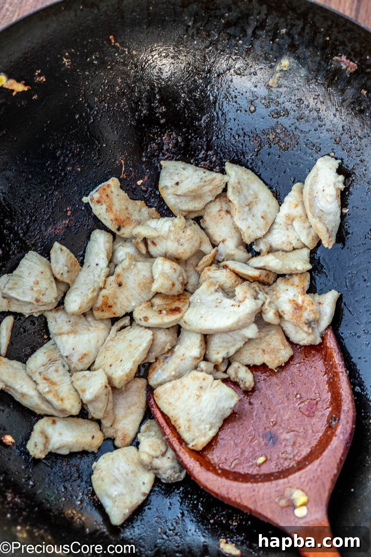 Golden-brown, bite-sized chicken pieces, perfectly seared in a wok, adding savory depth to the dish.