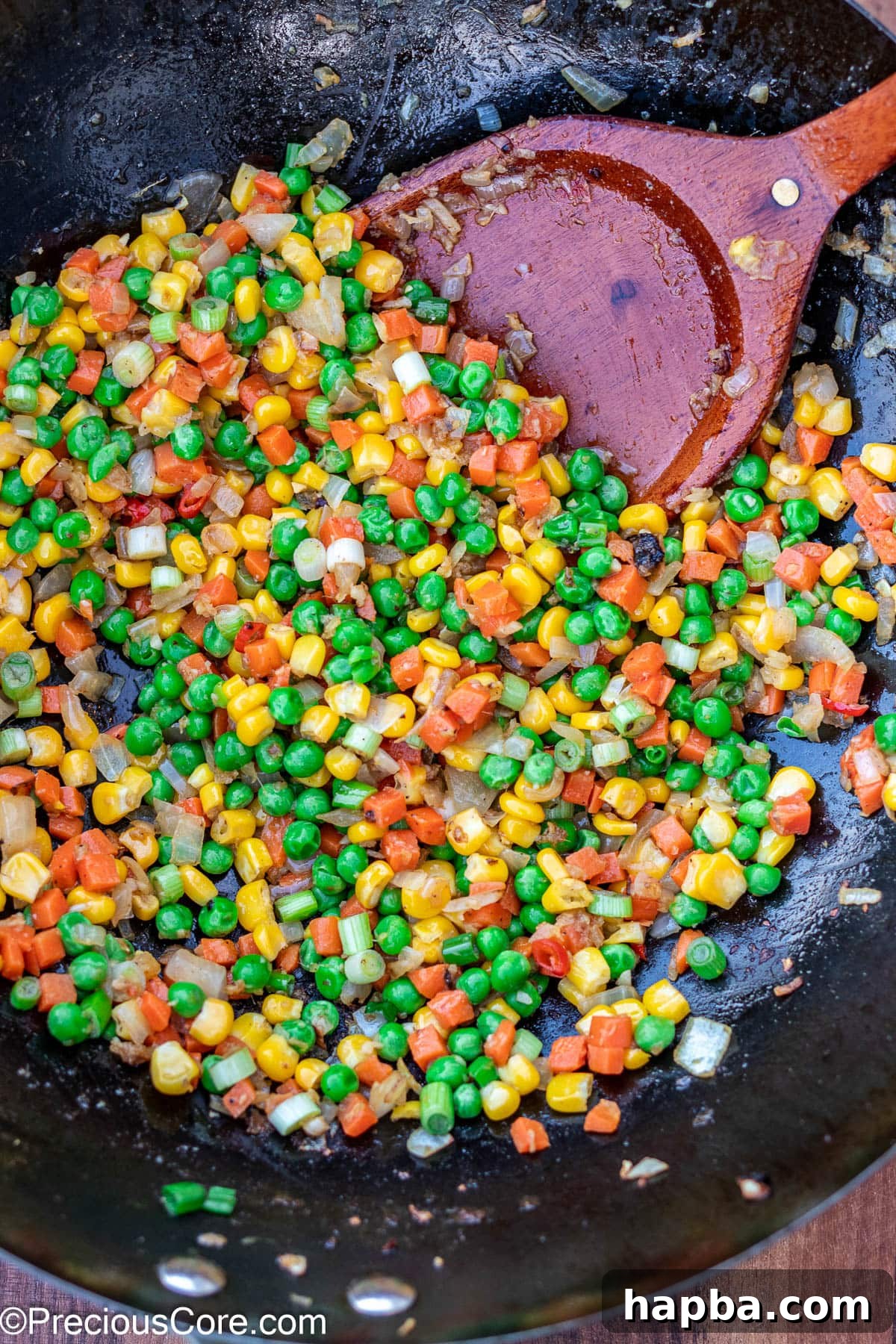 A colorful medley of stir-fried vegetables, including carrots, peas, and corn, sizzling invitingly in a hot wok.
