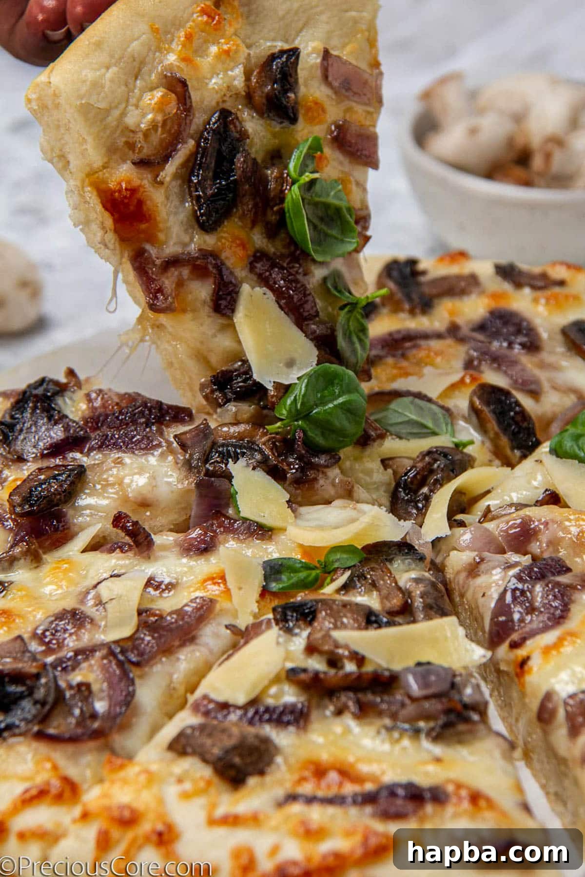 Delectable Mushroom Pizza 3 A hand reaching for a slice of freshly baked mushroom pizza, showing its golden crust and melted cheese.