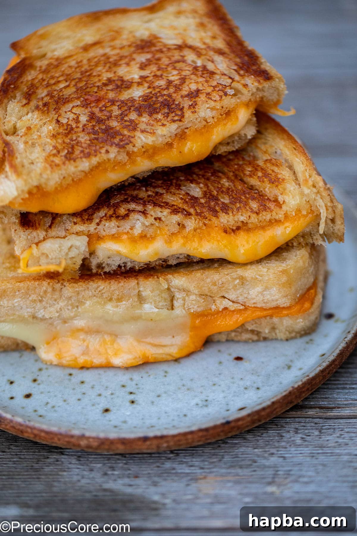 A stack of perfectly grilled sourdough cheese sandwiches, cut in half, showcasing their delicious layers.