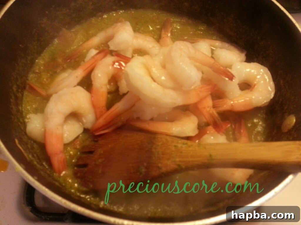 Shrimp mixing with the sauce in the pan.