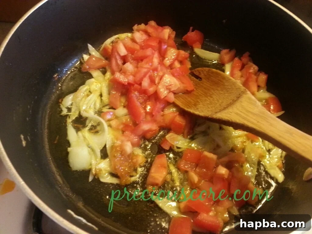 Tomatoes simmering in the pan, forming a sauce.