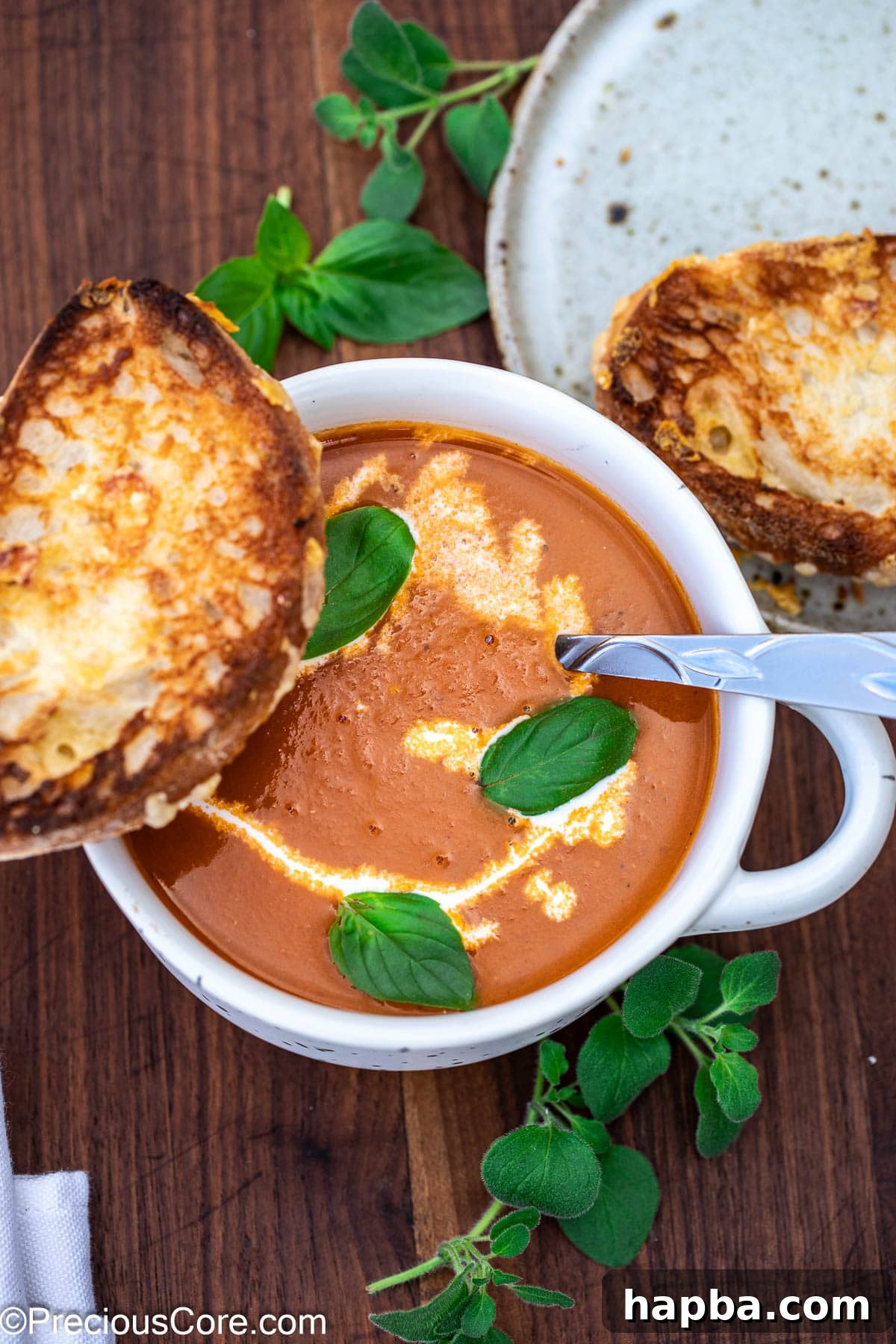 Cozy bowl of roasted tomato soup with heavy cream drizzled on top, ready to be enjoyed.