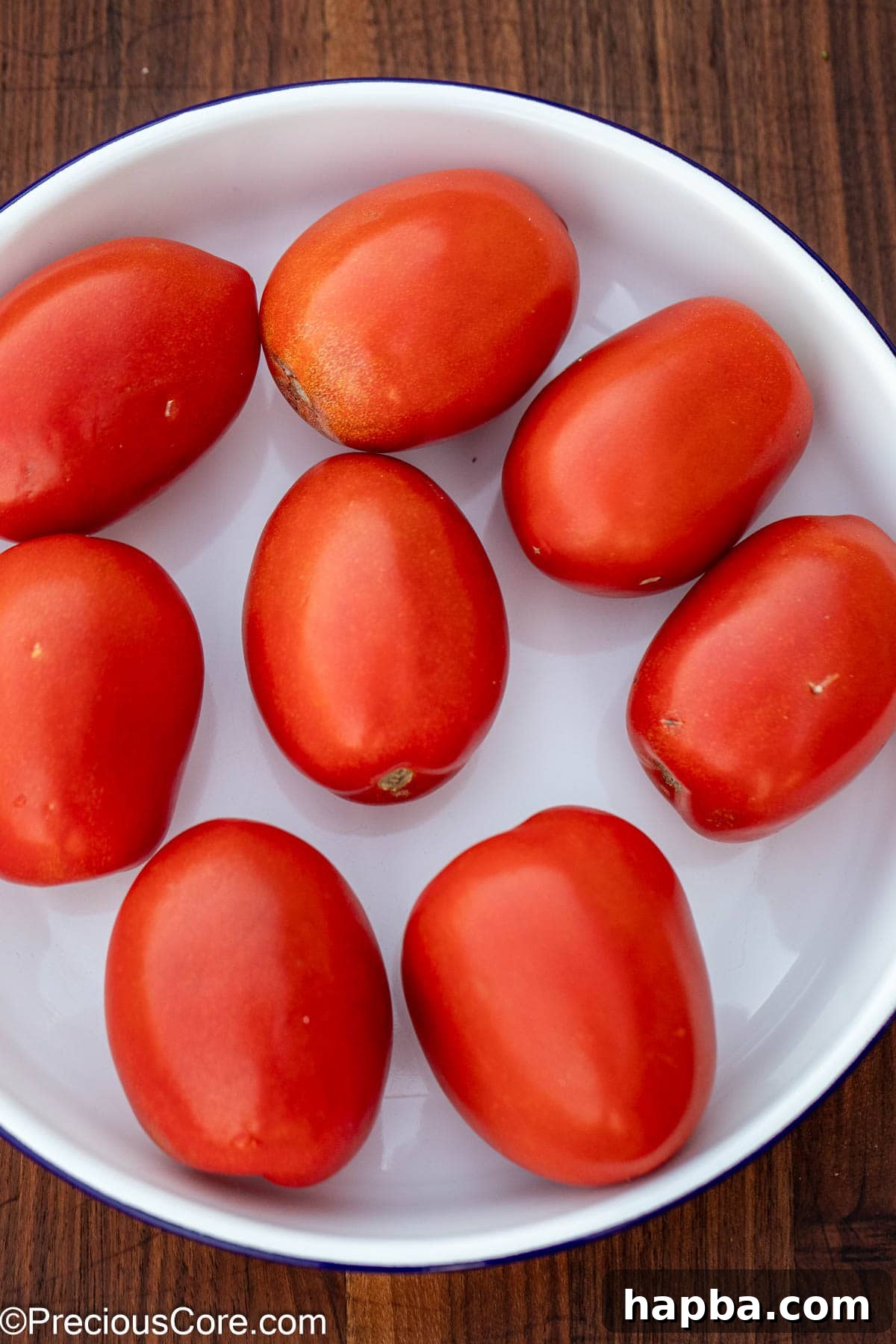Bright red Roma tomatoes in a white bowl, ready for roasting.